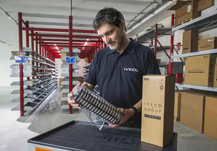 Magasinier tenant une pièce d'origine Iveco : Genuine Parts High Performance